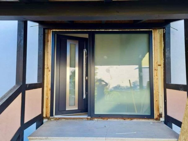 Moderne Haustür mit Glas-Seitenteil in einem Fachwerkhaus, teilweise renoviert.